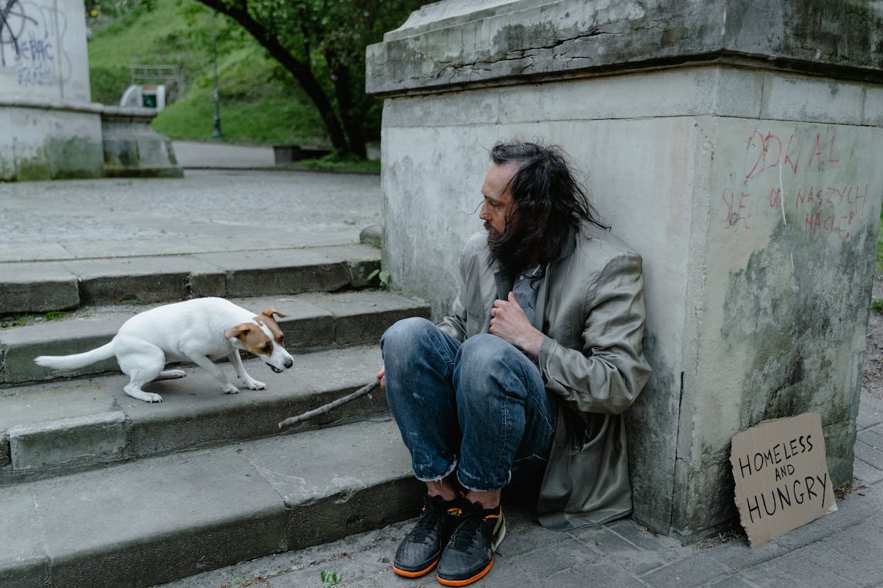 A homeless man and his dog in an outdoor urban setting highlighting companionship in poverty.